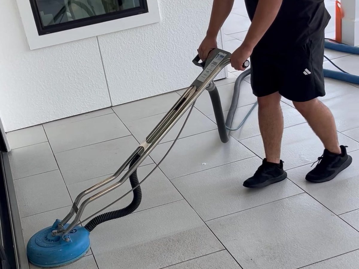 Technician cleaning tile and grout with professional equipment