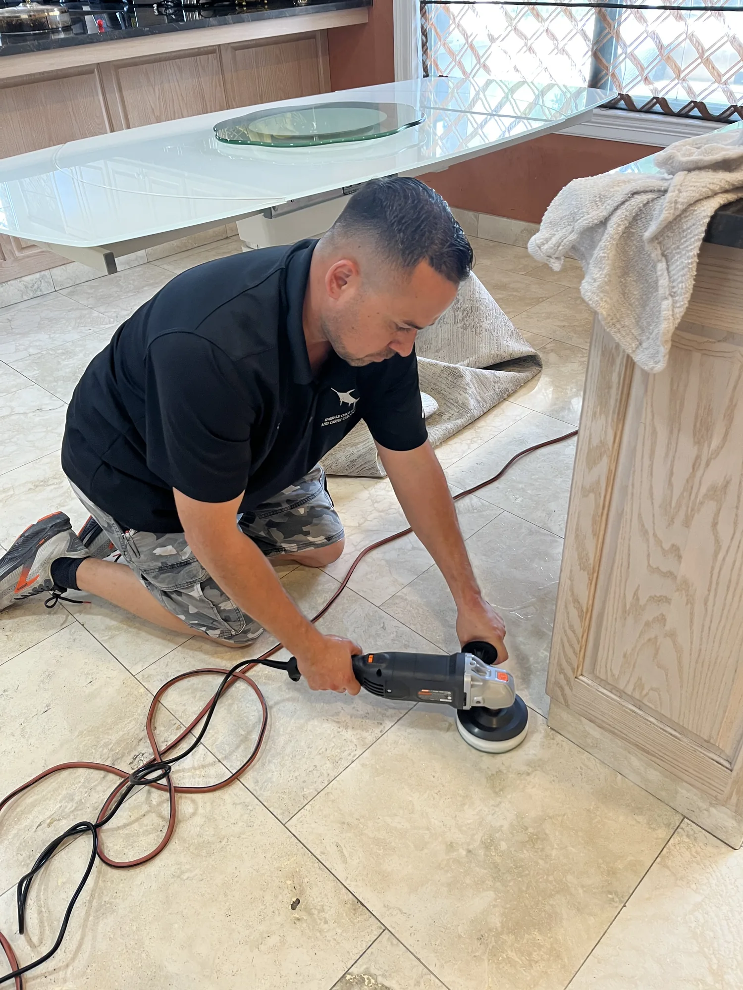 Technician using a handheld tool along cabinetry.