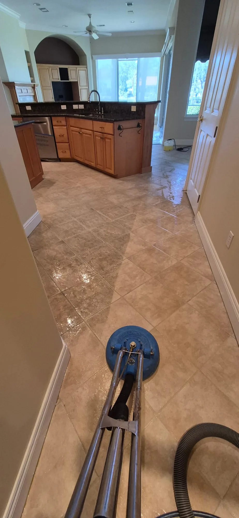 Tile cleaning in progress inside a home, with cabinetry and an adjoining room visible.