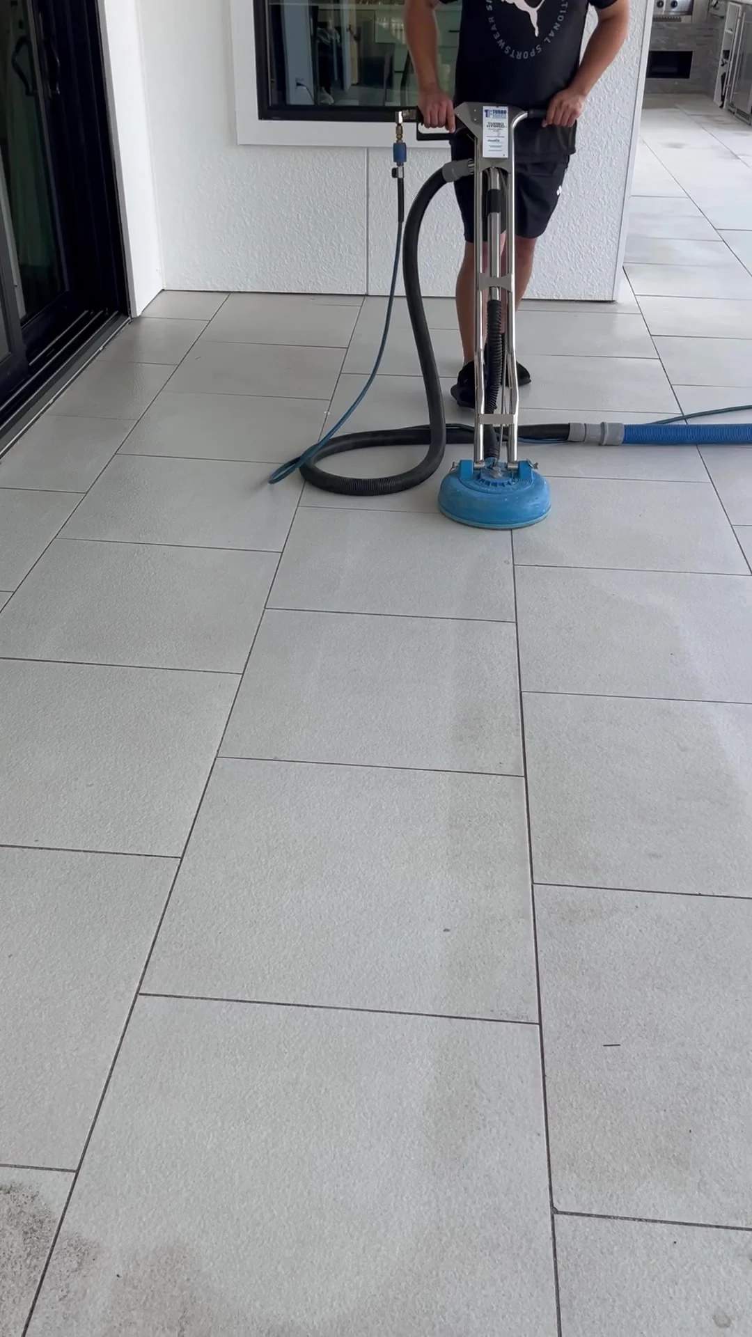 Technician using a rotary tile-cleaning tool on the Santa Rosa Beach patio.